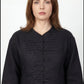 Inori Black Linen Top, black 100% linen mandarin collar blouse with frog-button knots, bell sleeves and adjustable corset-style lace-up back – back view