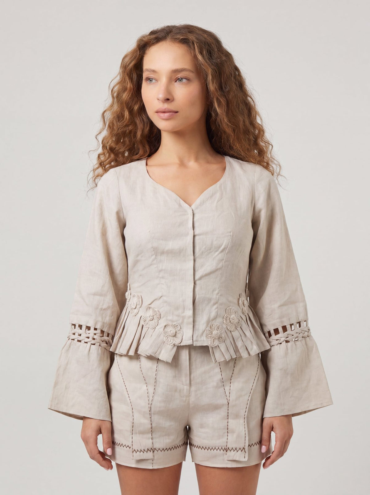 Rumi Top, handcrafted pure linen corset top with hand-braided sleeves, pleated ruffle hem and recycled floral appliques – styled on model
