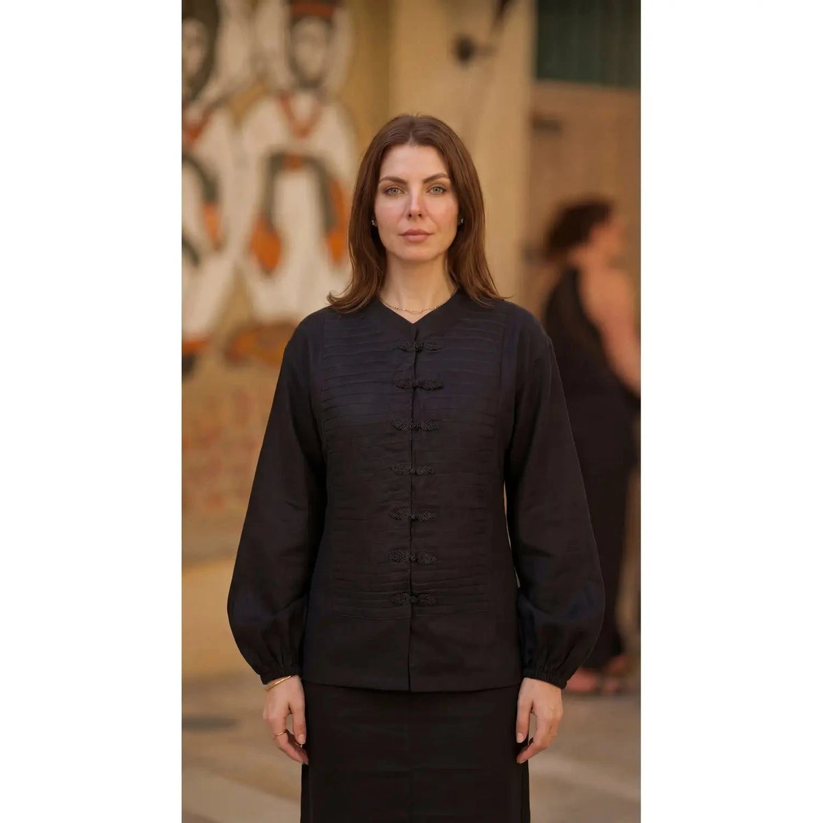 Inori Black Linen Top, black 100% linen mandarin collar blouse with frog-button knots, bell sleeves and adjustable corset-style lace-up back – styled on model
